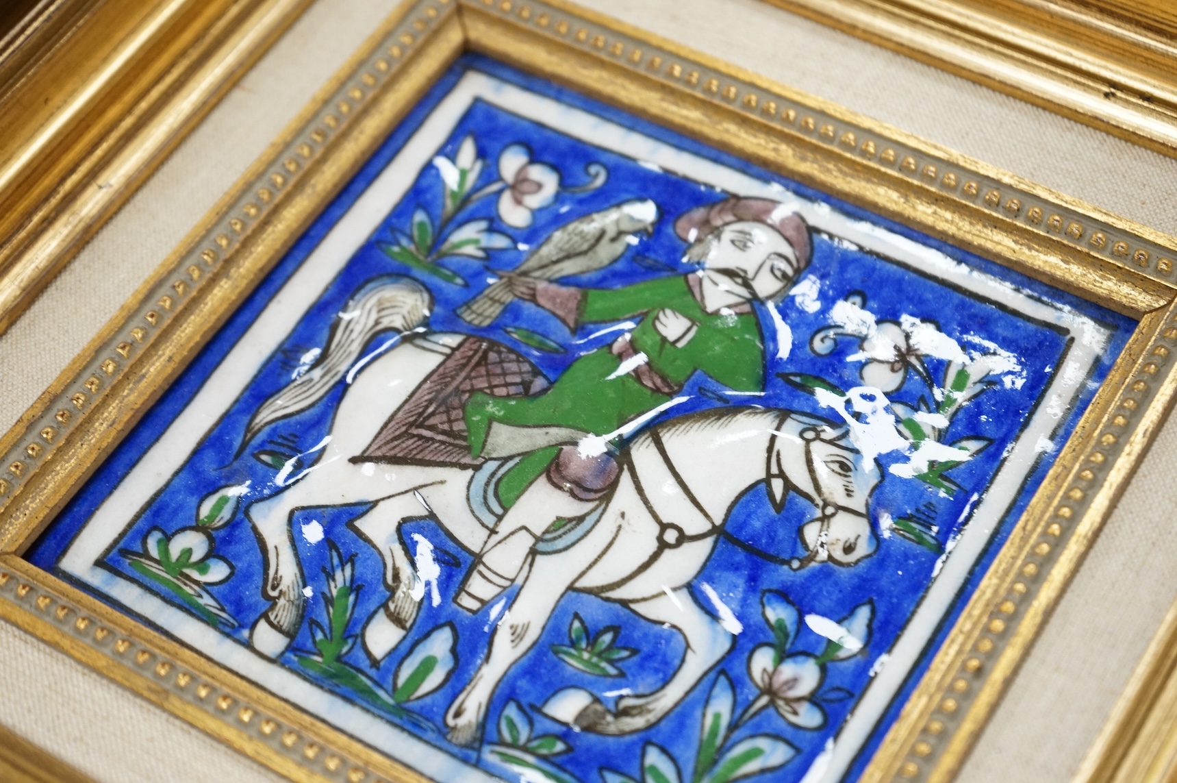 A pair of 19th century Persian fritware tiles depicting falconers, framed, 14cm squared